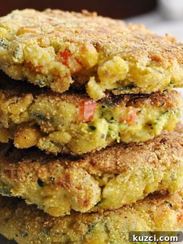 Four corn zucchini fritters with red peppers stacked on plate.