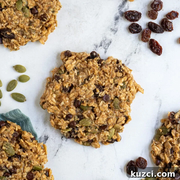 Breakfast cookies laid out on the table with one in the center filled with add-ins like seeds and raisins.