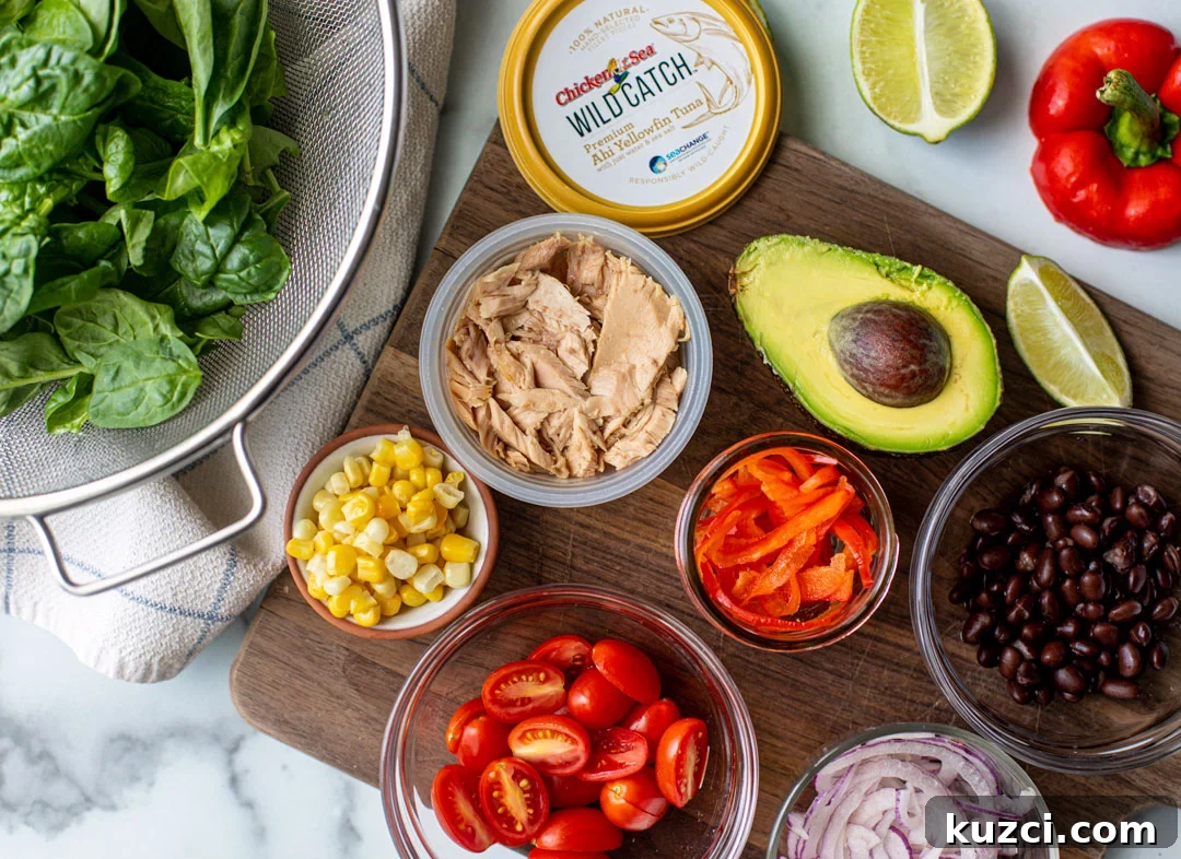 Ingredients sprawled out over marble background, including spinach, avocado, and other fresh veggies.