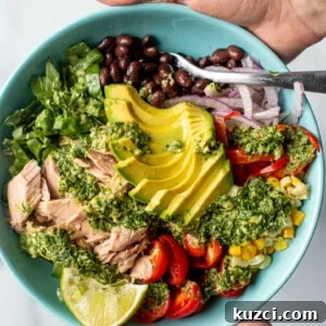 Colorful bowl of flaked tuna with vegetables and an herb dressing drizzled on top.