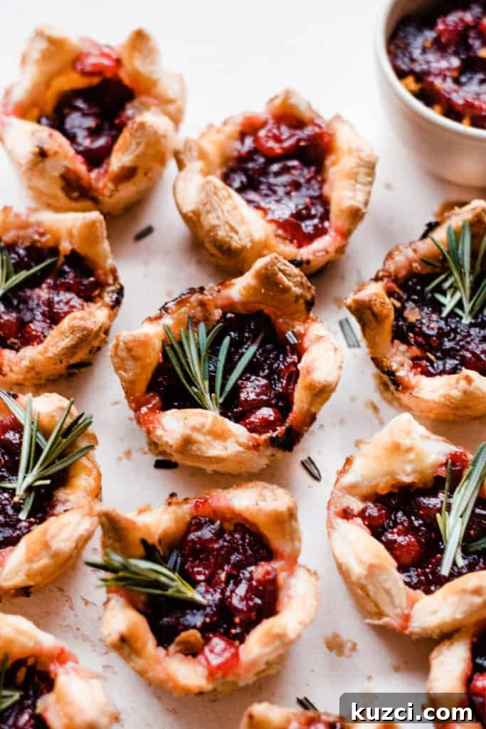 Gouda Puff Pastry Bites with Spiced Rum Cranberry Sauce 7 Puff Pastry Bites on a light surface, garnished with fresh rosemary