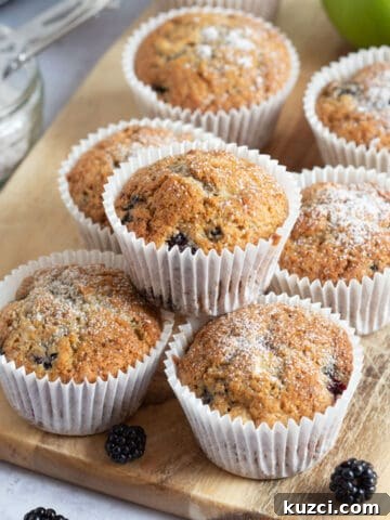 Apple and blackberry muffins on a wooden board.