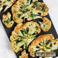 Roasted cauliflower steaks sprinkled with fresh parsley on a baking sheet.