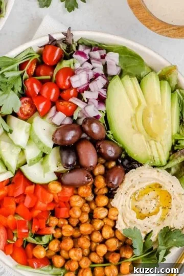Mediterranean salad in shallow salad bowl with side of tahini dressing.