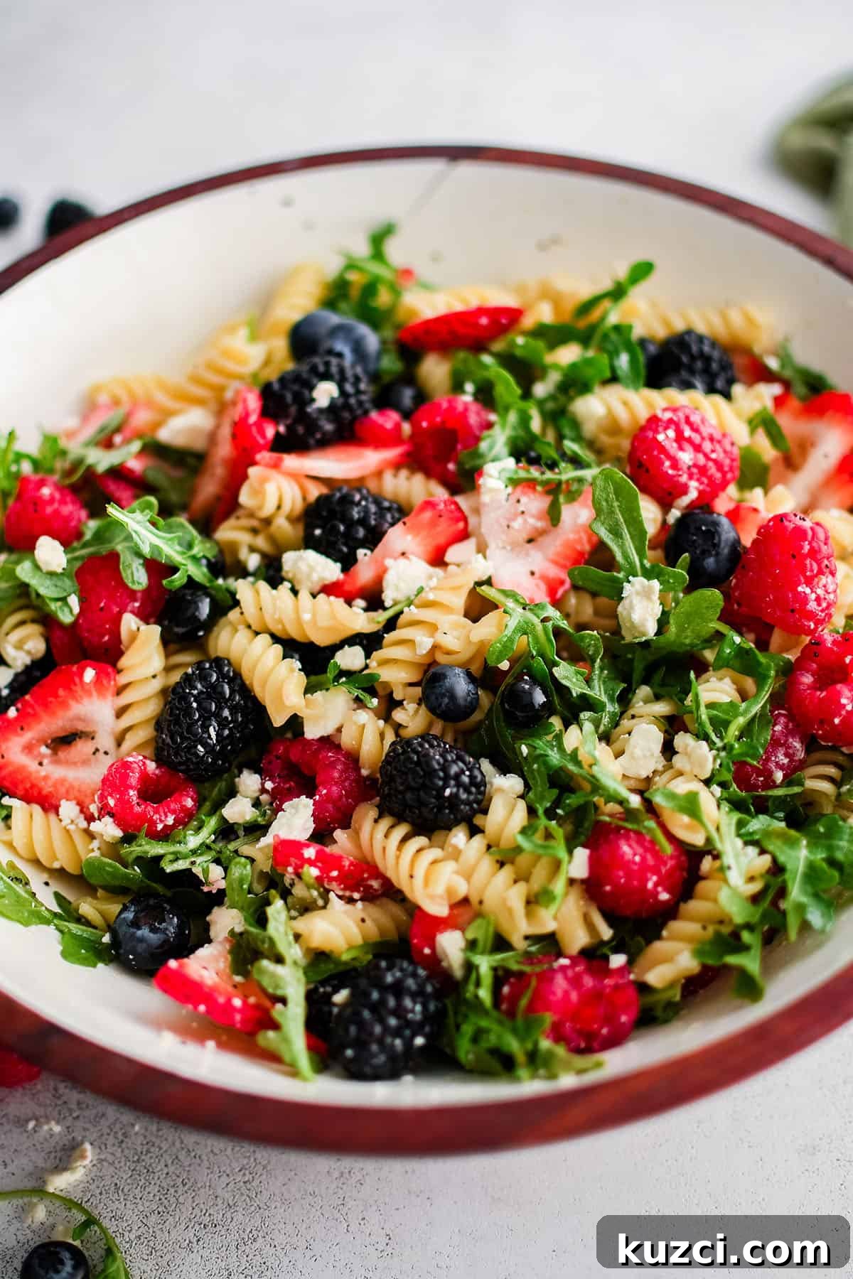 pasta salad with berries and arugula in a large bowl