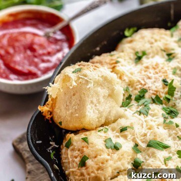 Parmesan bread bites in a cast iron pan with marinara sauce next to it.