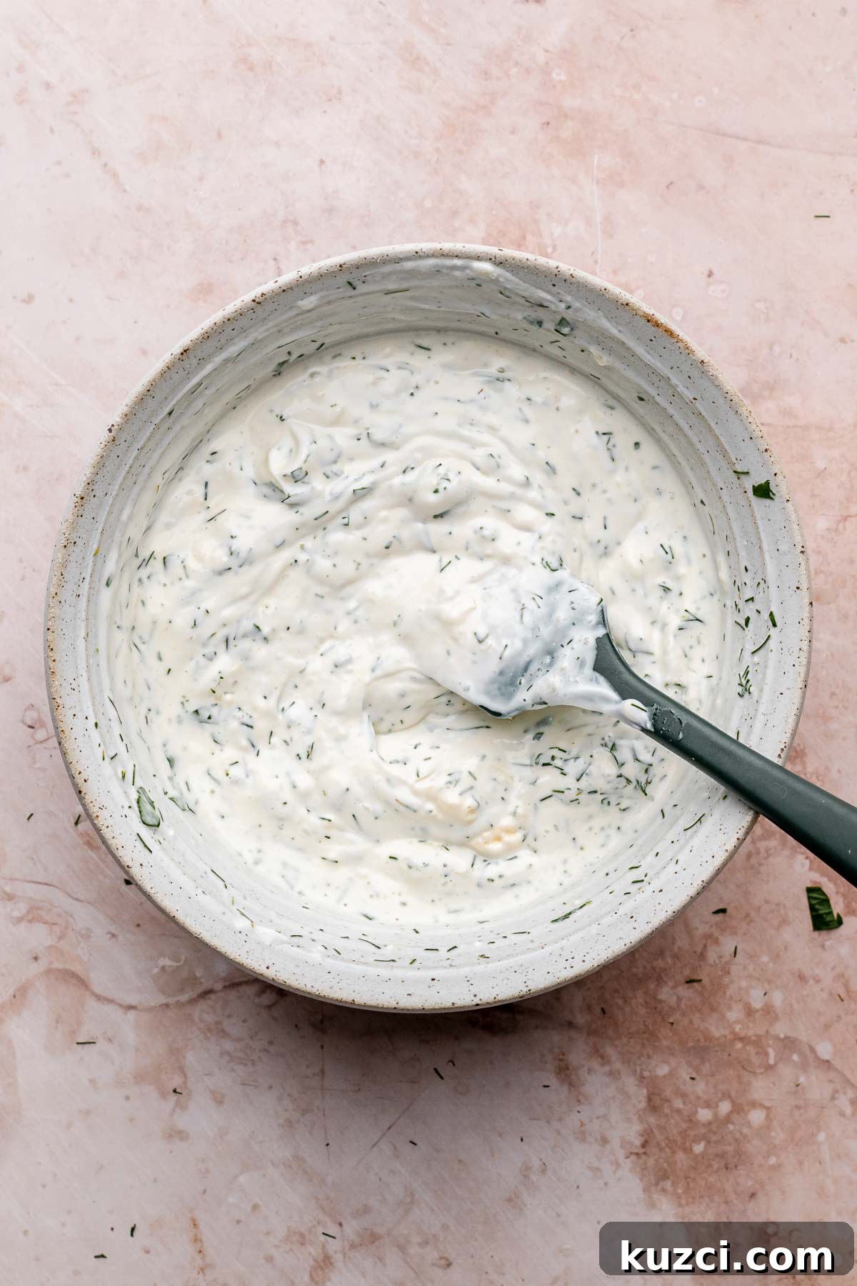 Crispy Corn and Zucchini Fritters with Herbed Yogurt Sauce 7 Herb yogurt sauce in a bowl with a spatula.