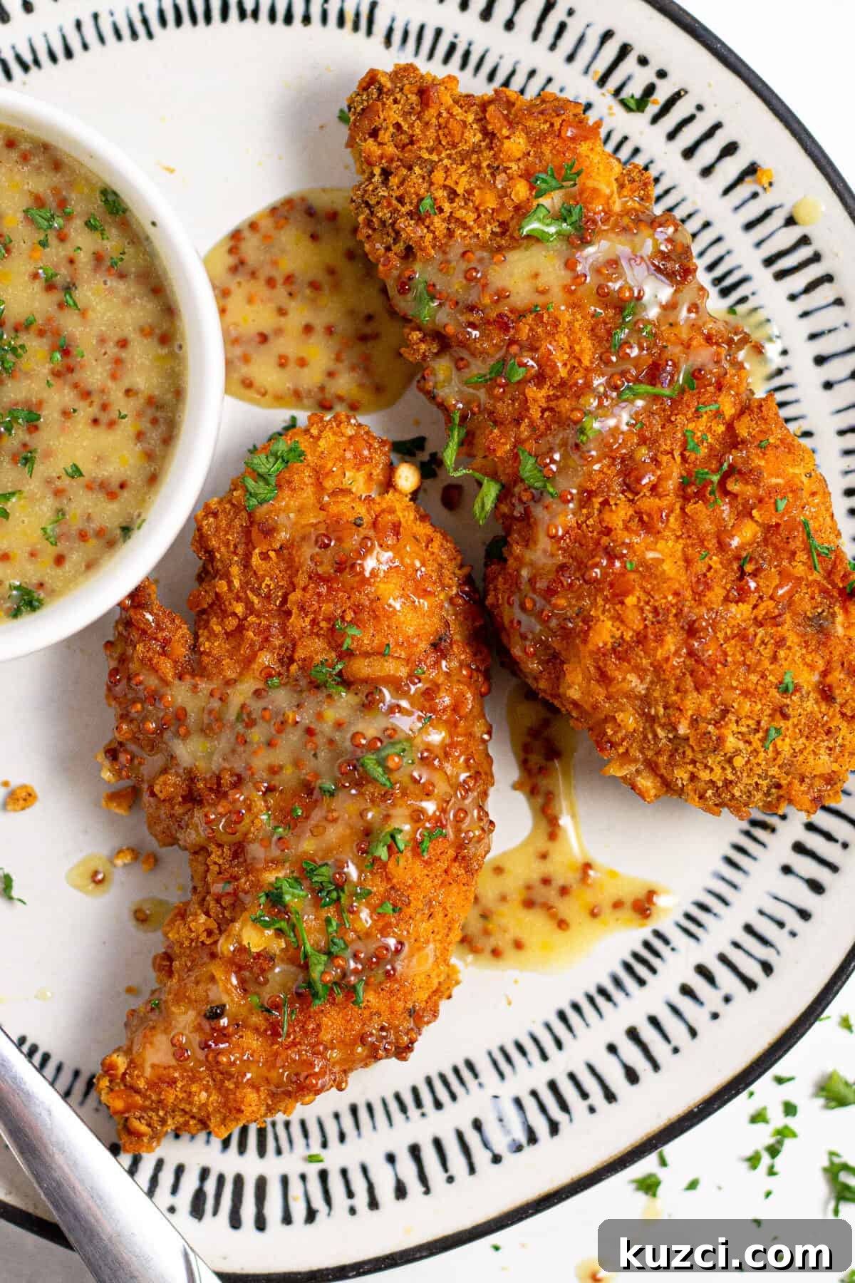 Crispy Oven Fried Chicken Tenders 2 Overhead shot of baked chicken tenders on a white plate garnished with fresh parsley