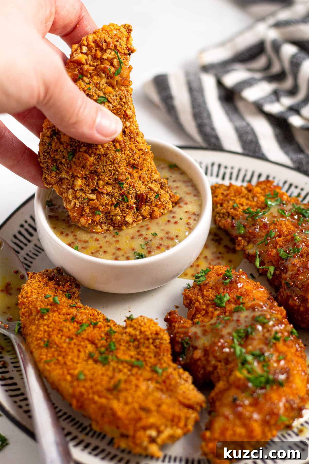 Crispy Oven Fried Chicken Tenders 9 Close up shot of a baked chicken tender being dunked into honey mustard sauce