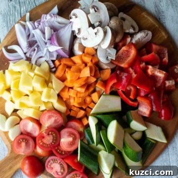 Italian Roasted Vegetables Recipe 4 Assortment of colorful chopped vegetables on a round wooden board.