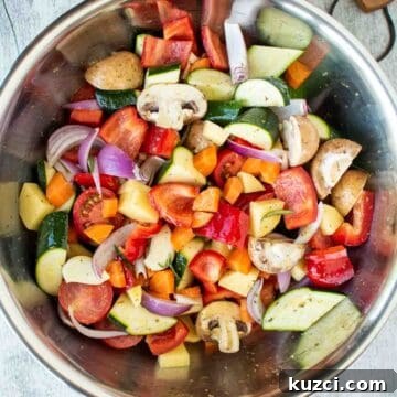 Italian Roasted Vegetables Recipe 6 Assorted chopped vegetables in a stainless steel bowl viewed from above.