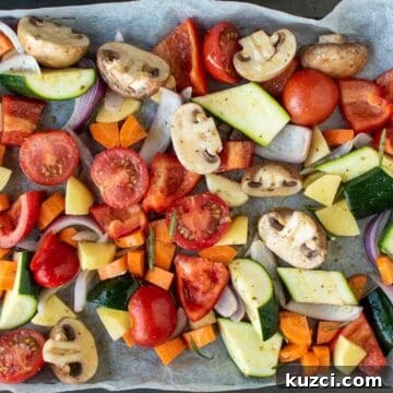 Italian Roasted Vegetables Recipe 7 Assorted chopped vegetables in a single layer on a baking sheet viewed from above.