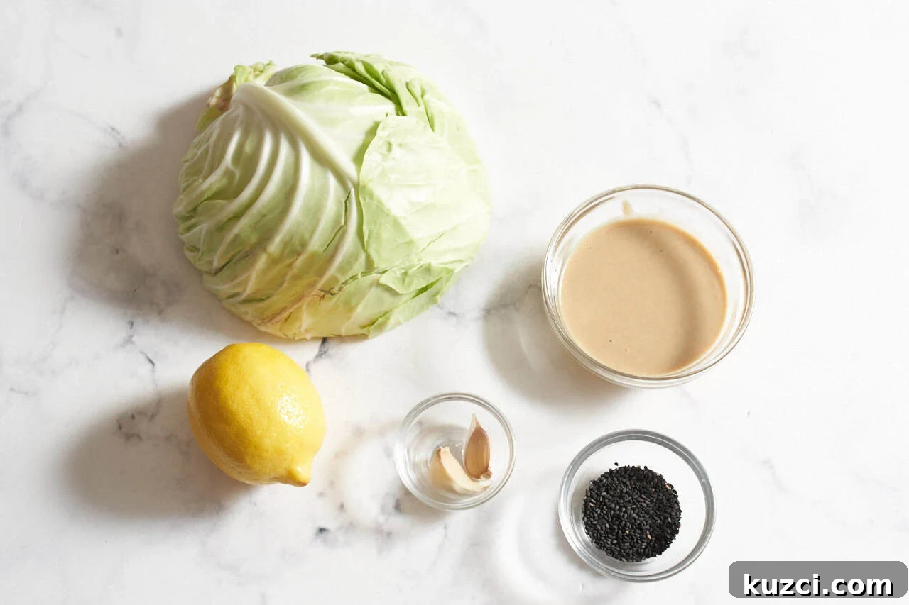 Charred Sheet Pan Cabbage with Tahini Sauce 3 Half a cabbage, a lemon, and small bowls of tahini, garlic cloves, and black sesame seeds.