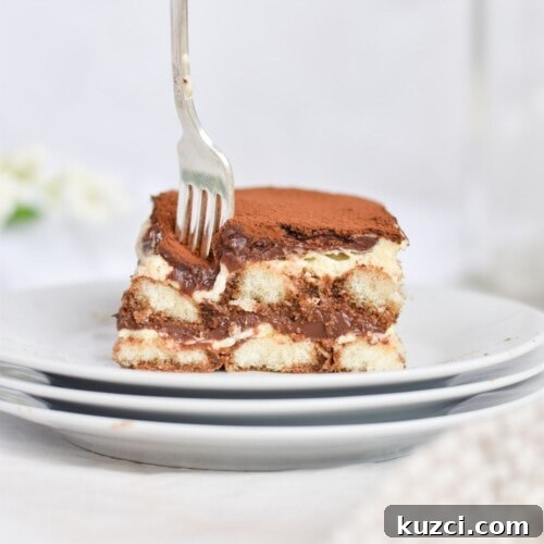 fork going into a slice of tiramisu on white plate.