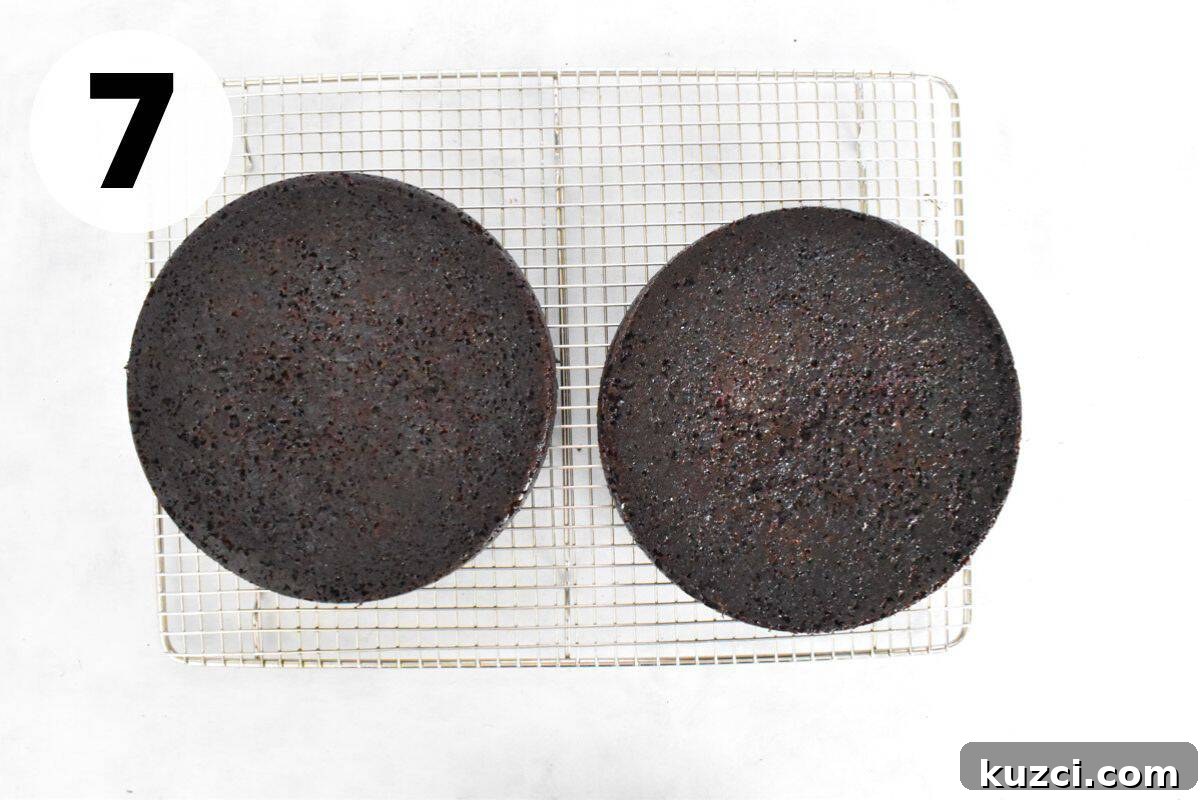 two round chocolate cakes cooling on a wire rack.