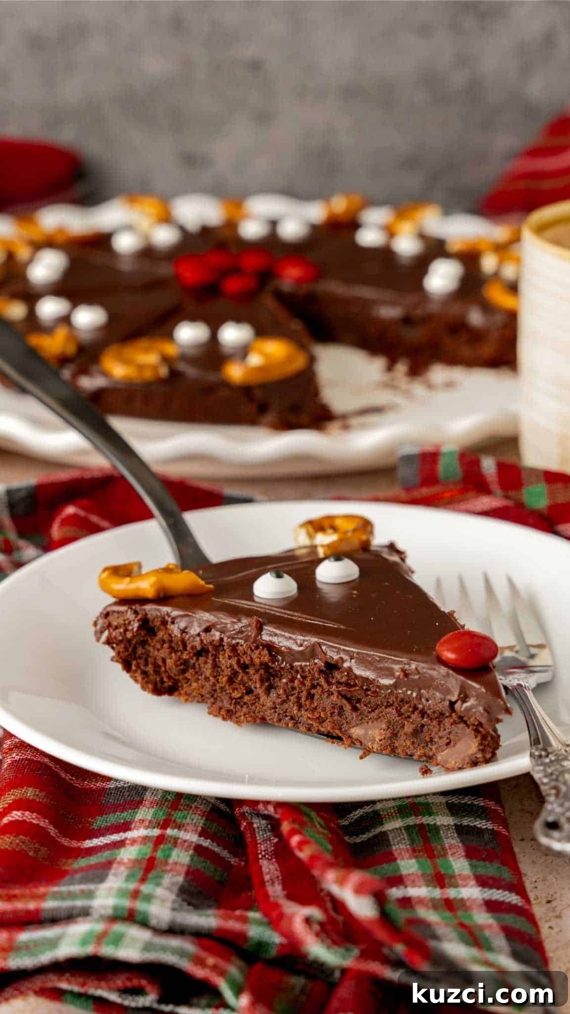 A Rudolf Reindeer Brownie glazed with chocolate ganache with a face on a white saucer.