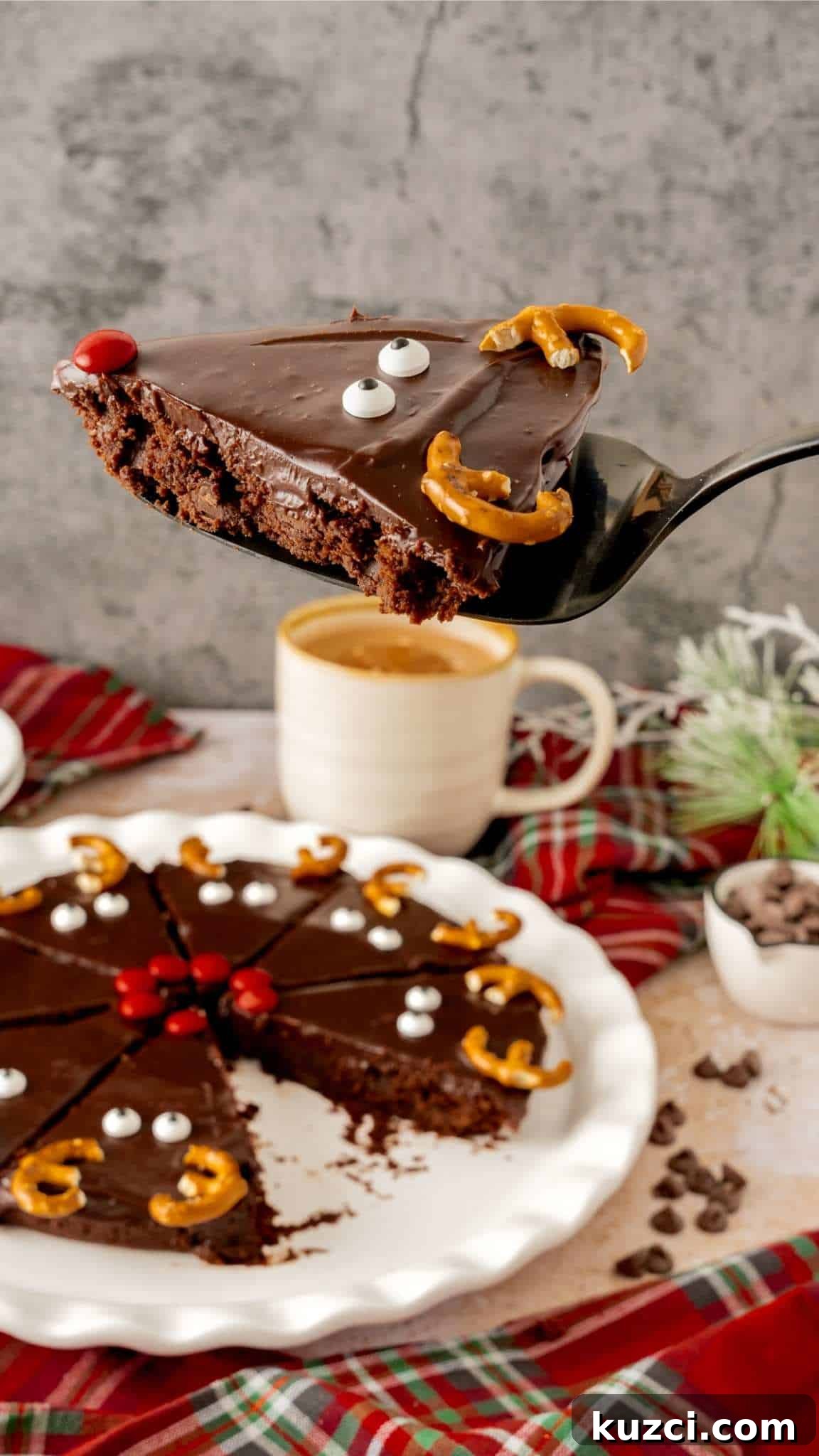 A Reindeer brownie on a pie server hovering above a plate of Christmas brownies.