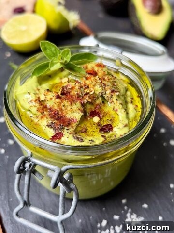 Close-up of avocado mayo topped with red chilli flakes, oregano top, mixed pepper grounded and a drizzle of olive oil.