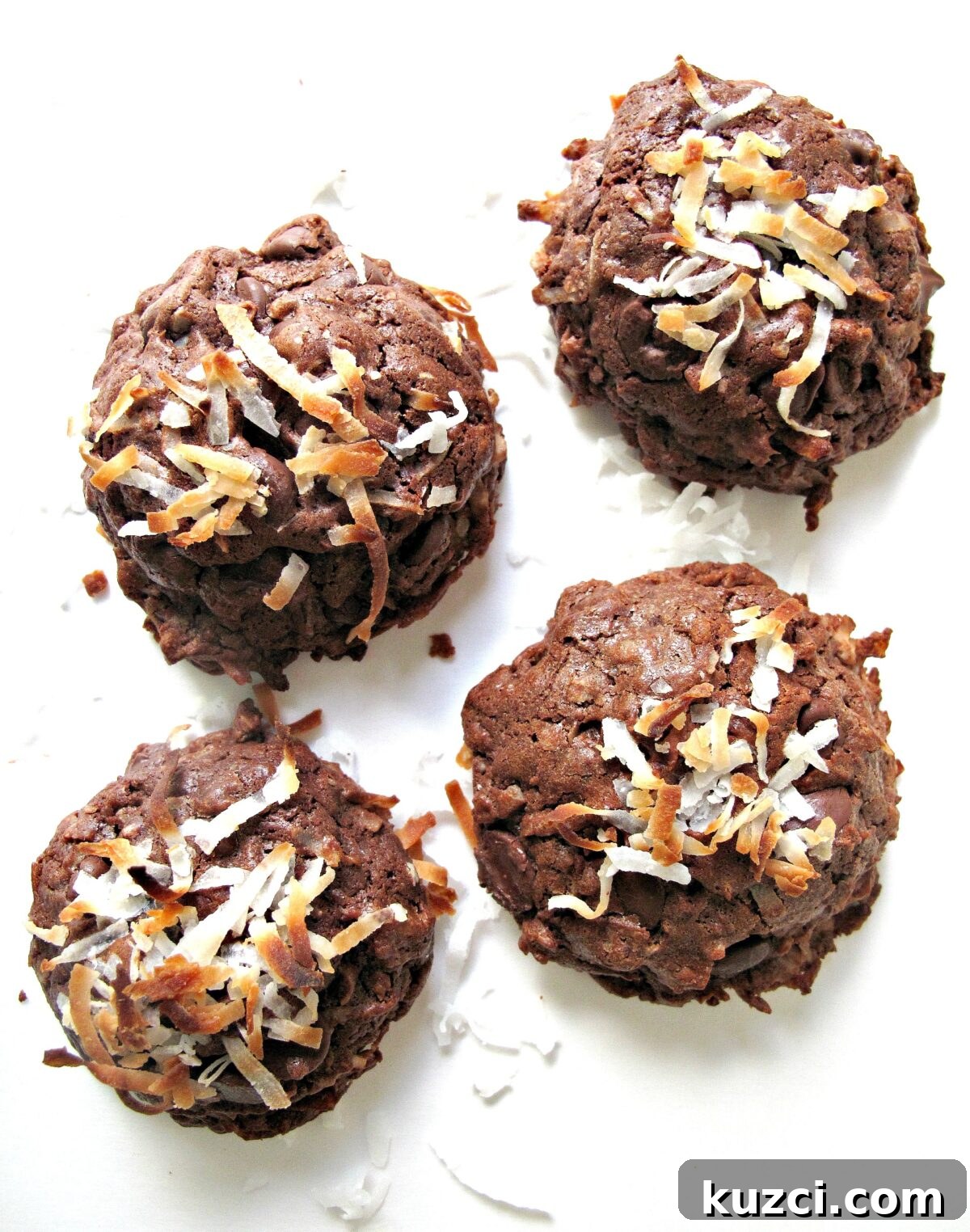 Chocolate Coconut Bliss Cookies - chewy fudgy chocolate cookie with coconut inside and out. Overhead photo of 4 coconut topped chocolate cookies.