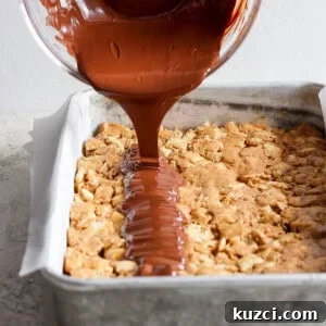 Peanut Butter Chex Bars Recipe 13 Chocolate sauce being poured onto a tray of baked dessert bars.