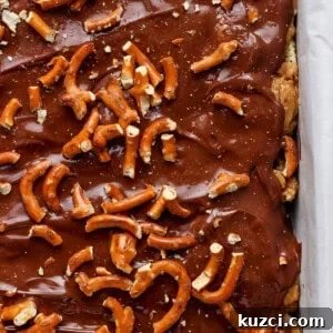 Peanut Butter Chex Bars Recipe 14 A tray of chocolate-covered toffee topped with pretzels.
