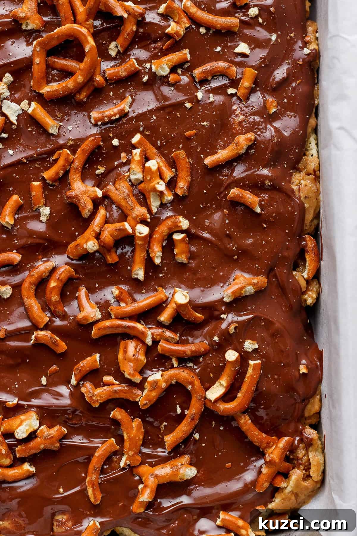 Peanut Butter Chex Bars Recipe 5 A tray of chocolate-covered toffee topped with pretzels.
