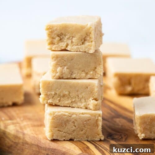 four pieces of peanut butter fudge stacked on top of each other on a wooden serving tray.