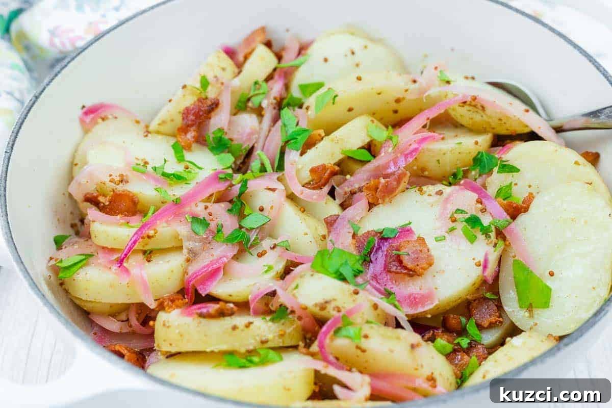 33 Fall Dinner Recipes Packed With Comfort Food Favorites 12 German Potato Salad with red onions, and bacon pieces, garnished with chopped parsley are served in a white dish with a spoon.