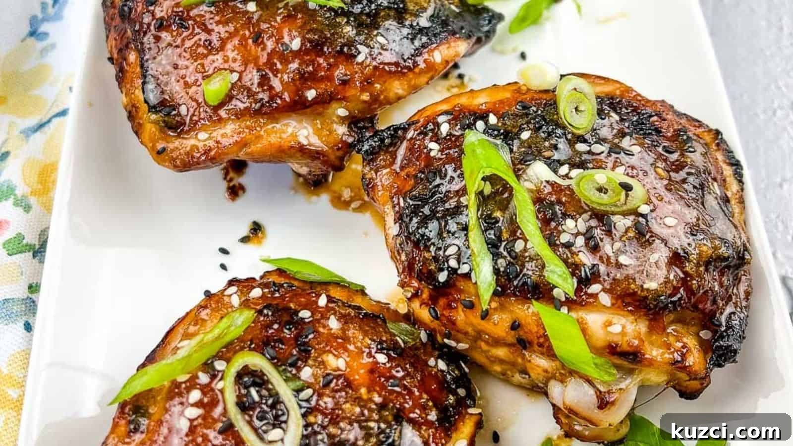 33 Fall Dinner Recipes Packed With Comfort Food Favorites 13 Three pieces of Air Fryer Honey Garlic Chicken garnished with sesame seeds and chopped green onions on a white rectangular plate.
