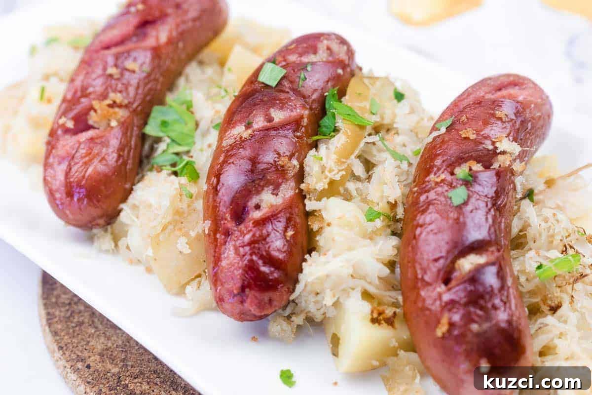 33 Fall Dinner Recipes Packed With Comfort Food Favorites 8 Three grilled sausages served on a bed of sauerkraut and diced potatoes, garnished with chopped parsley on a white plate.