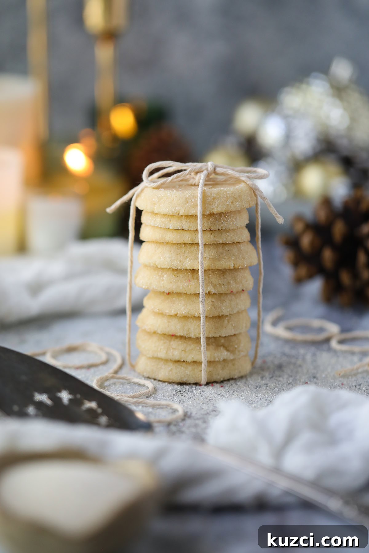 Cardamom Butter Cookies Recipe 2 Cardamom butter cookies stacked on a table with pinecones and candles in the background.