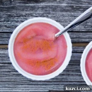 How to Make Unsweetened Applesauce from Scratch 9 Pink applesauce in a white bowl with a spoon.