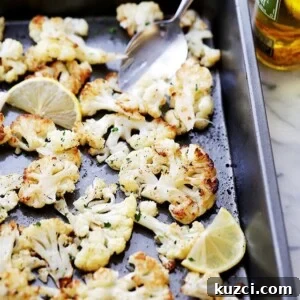 Lemon Roasted Cauliflower Recipe 2 Overhead view of roasted cauliflower seasoned with lemon, paprika, and thyme on a baking sheet.