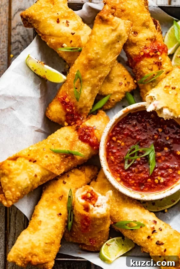 crab rangoon egg rolls in a basket with a bowl of sweet and sour dipping sauce.