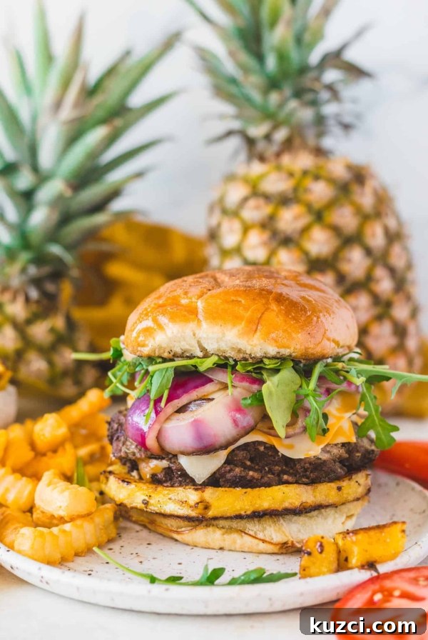 burger and fries on a plate with pineapples in the background