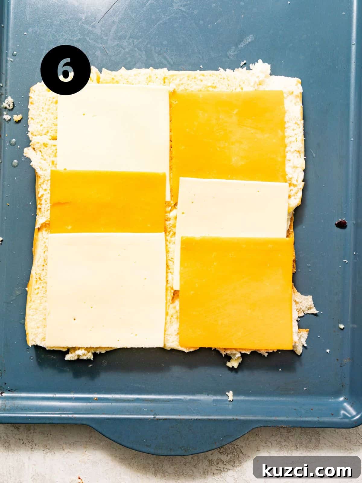 american cheese and cheddar cheese slices spread across the hawaiian rolls.