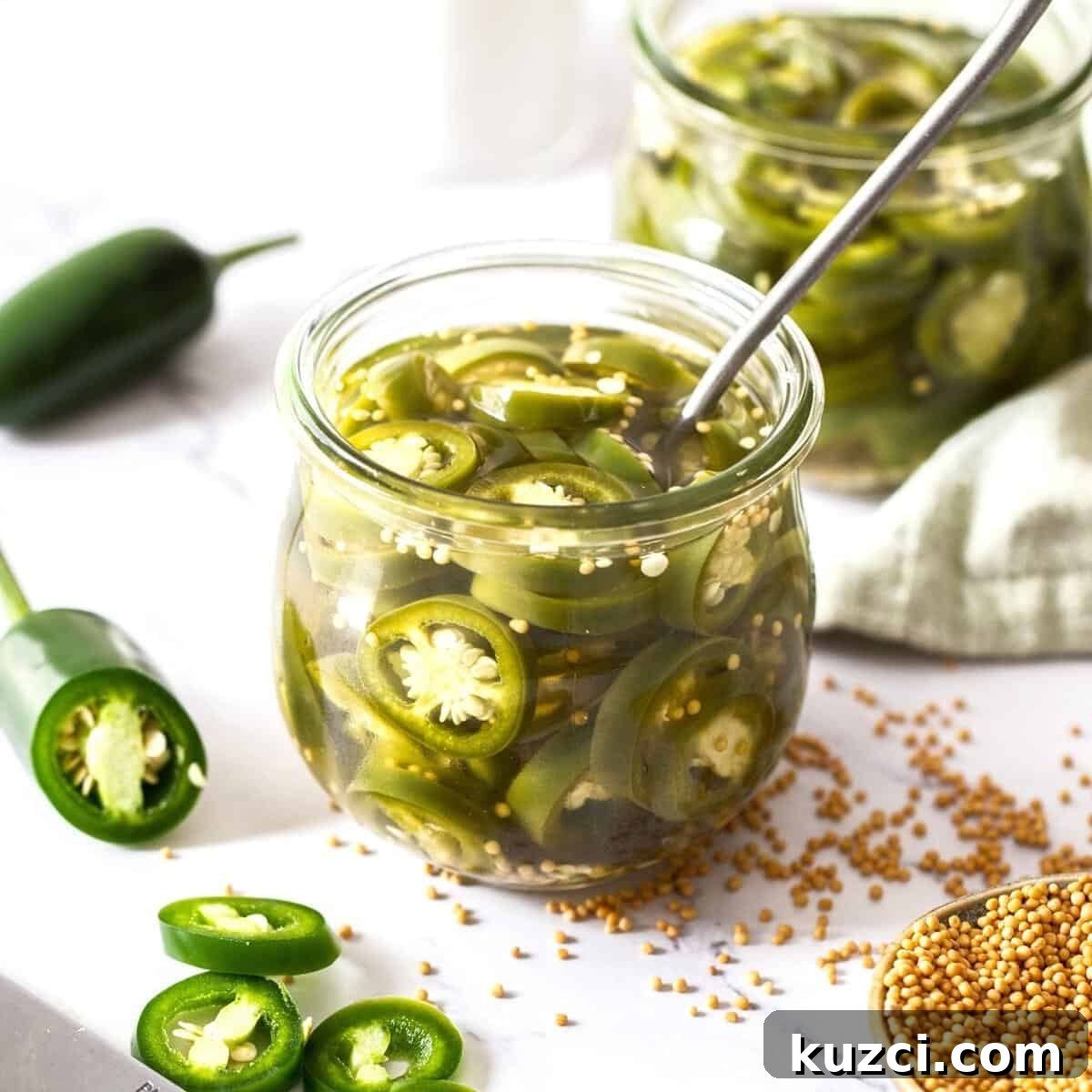 Jar of pickled jalapeños with a spoon sitting in jar, with some fresh jalapeños around the edge.
