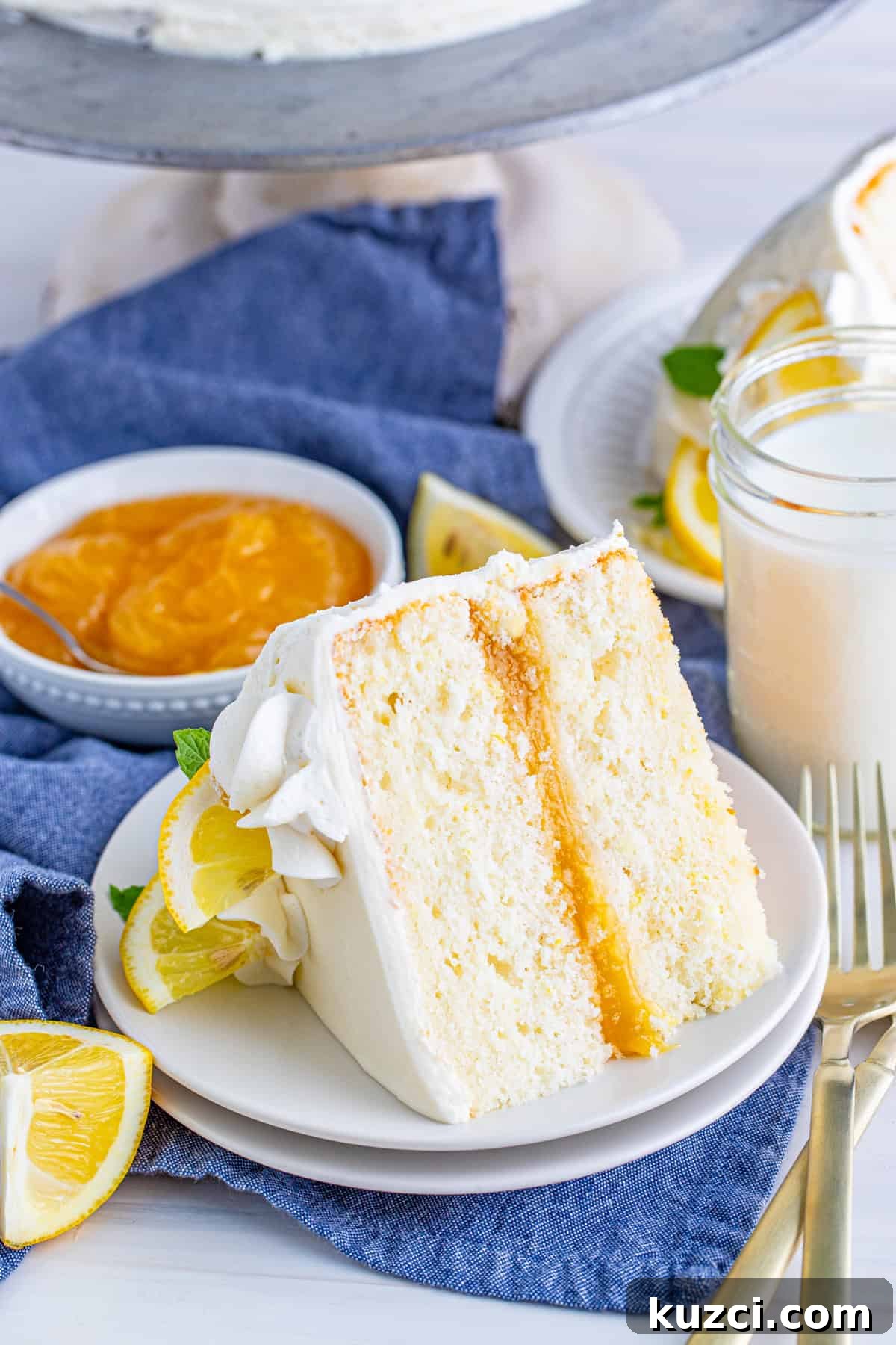Zesty Lemon Layer Cake with Silky Buttercream 2 One slice of Lemon Layer Cake on white plate with lemon curd in background