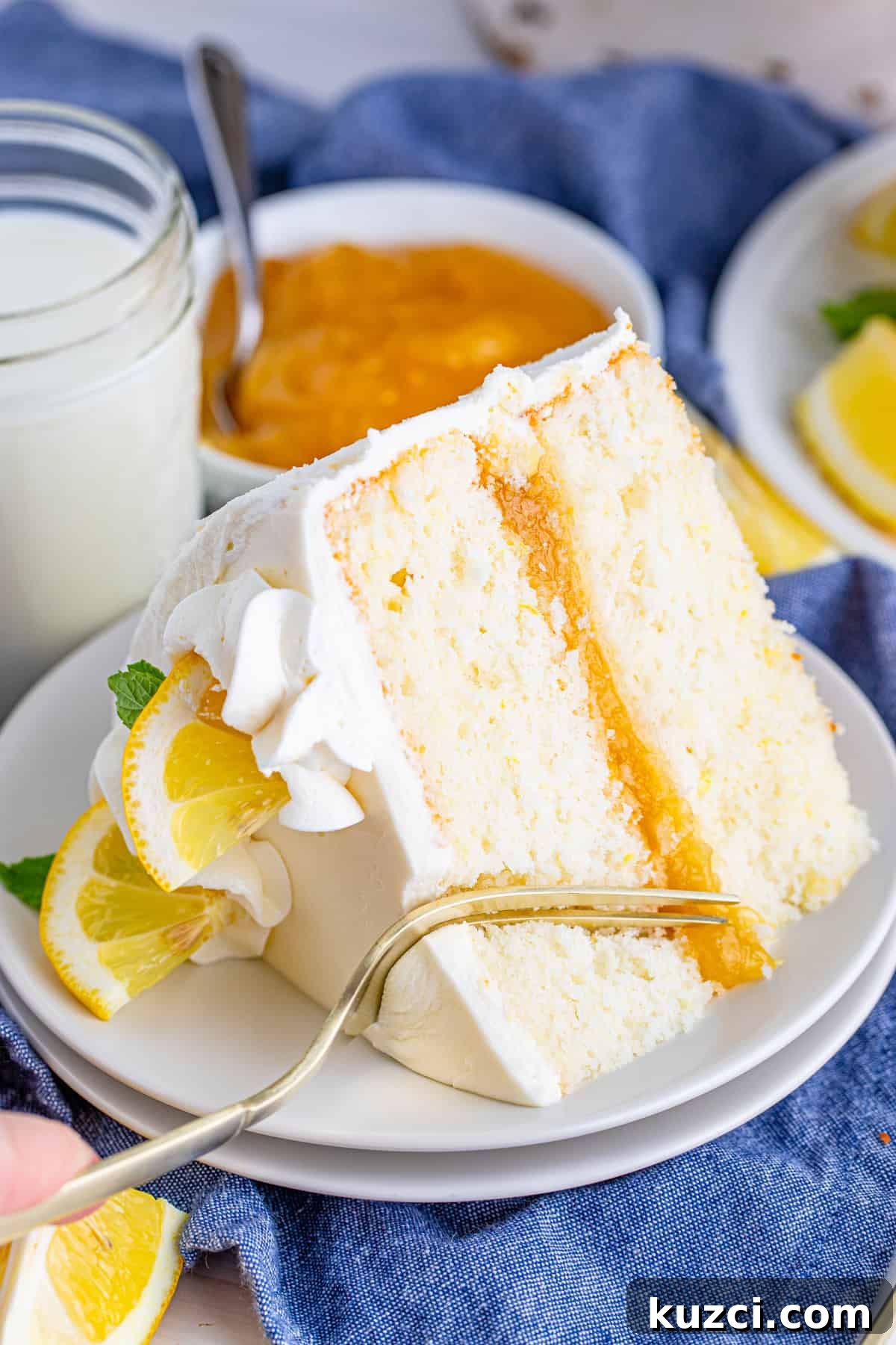 Zesty Lemon Layer Cake with Silky Buttercream 7 Fork cutting a bite out of a slice of Lemon Layer Cake