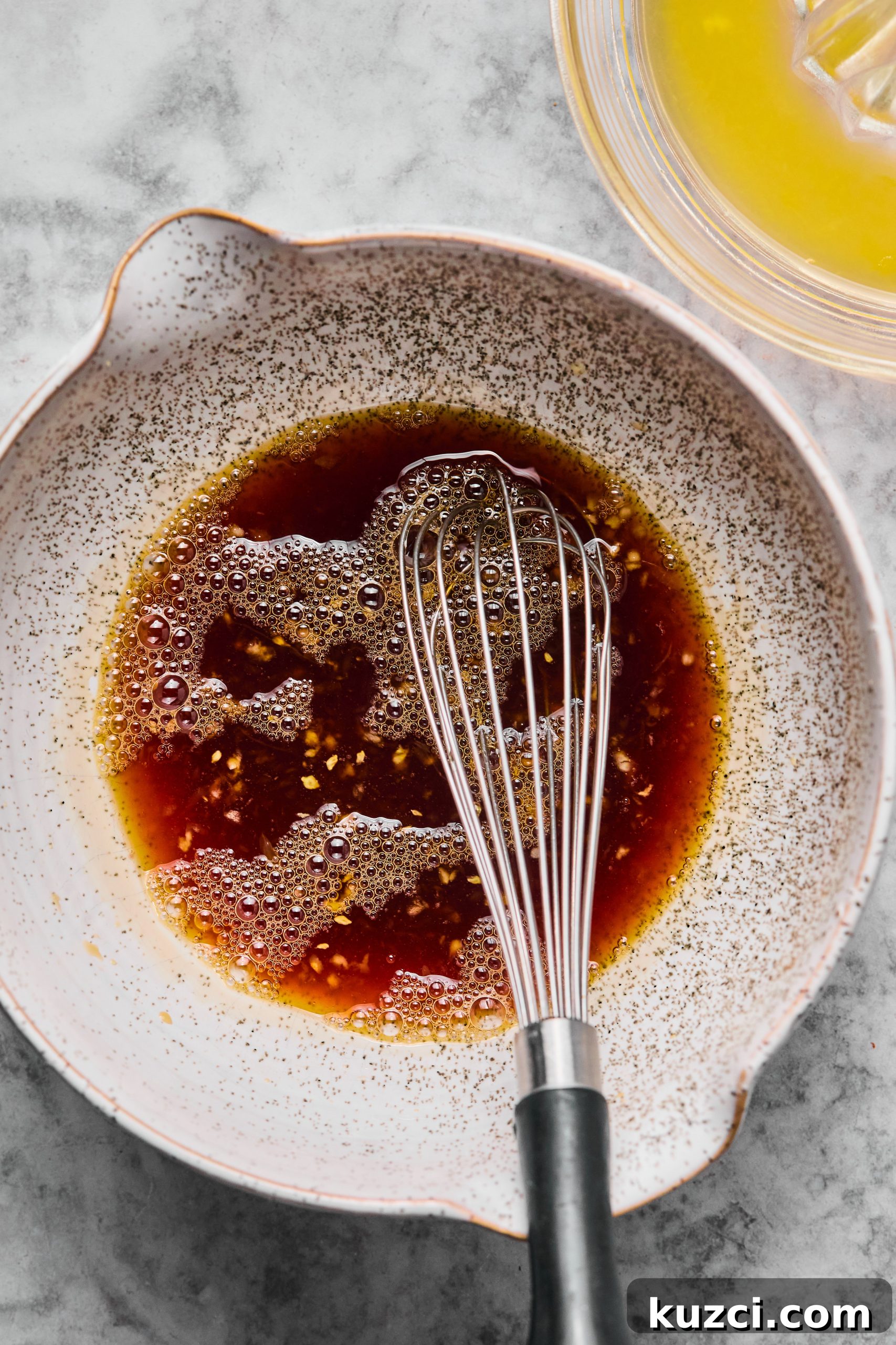 A small gray bowl filled with orange honey sauce used to make cilantro orange chicken bites