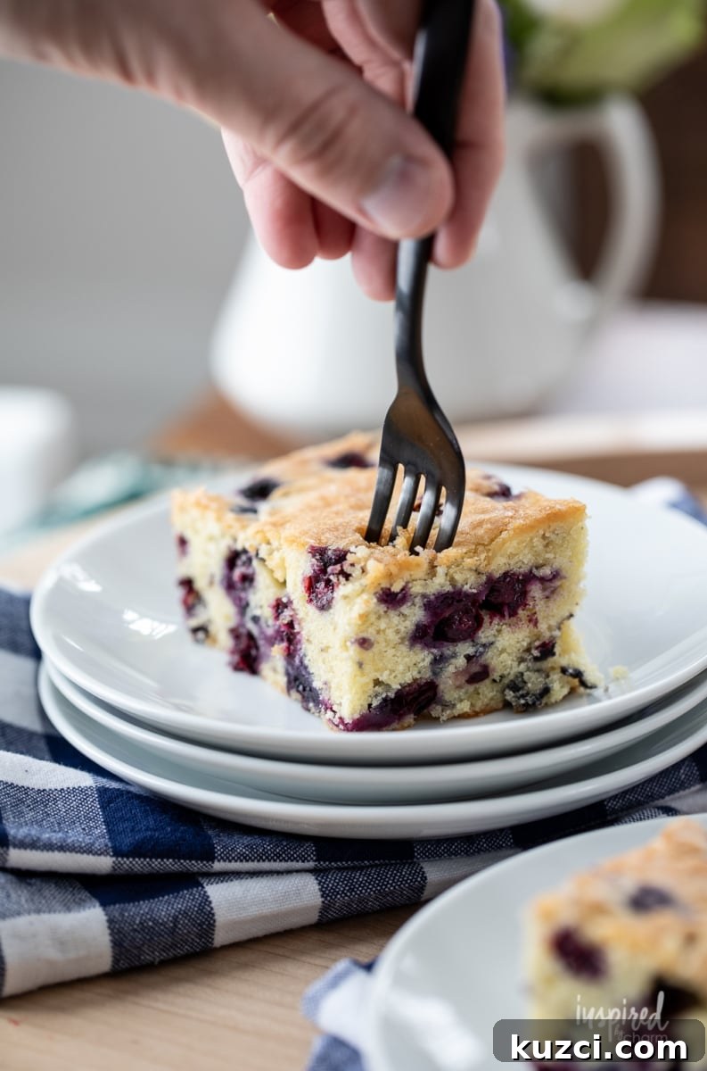 Moist Blueberry Cake Recipe with Lemon Glaze 9 using a fork to get a bite size piece of blueberry cake