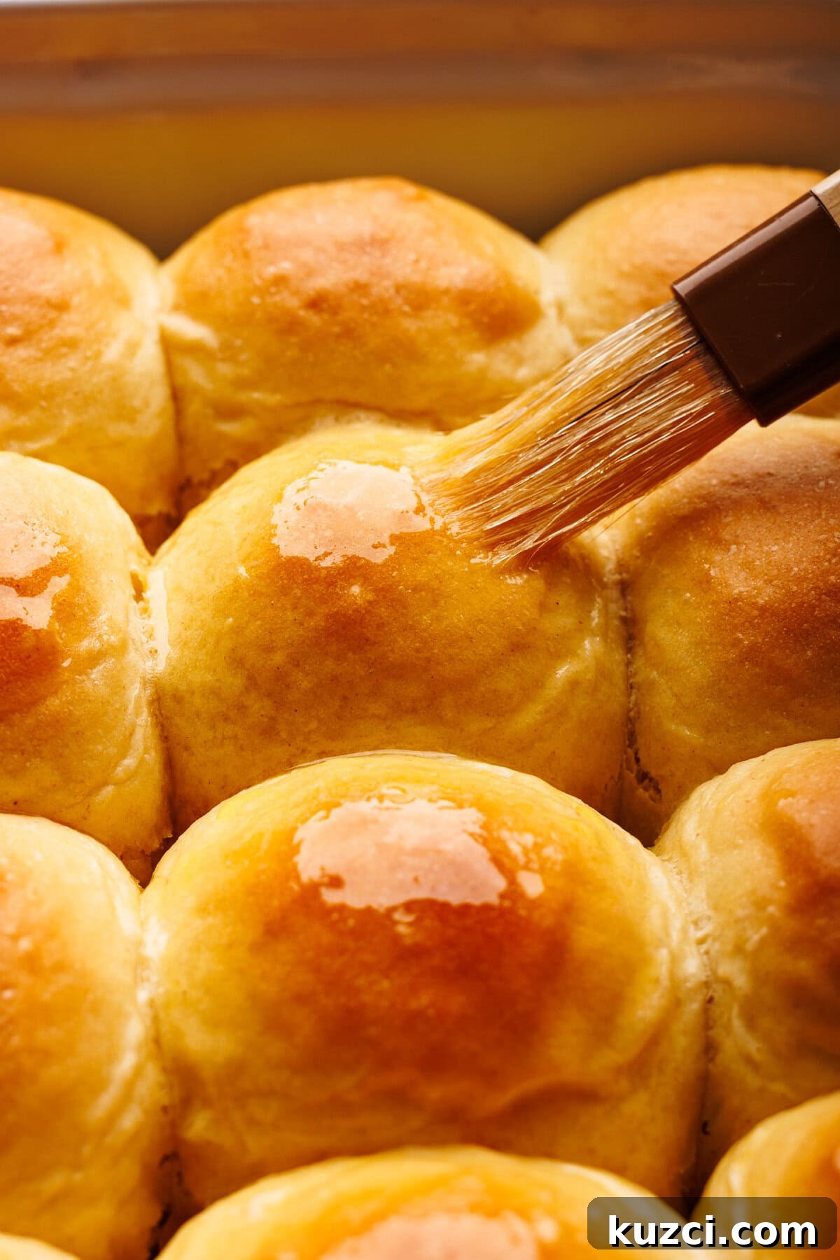 Soft, Buttery Homemade Dinner Rolls Recipe 6 A close up of dinner rolls being brushed with melted butter.