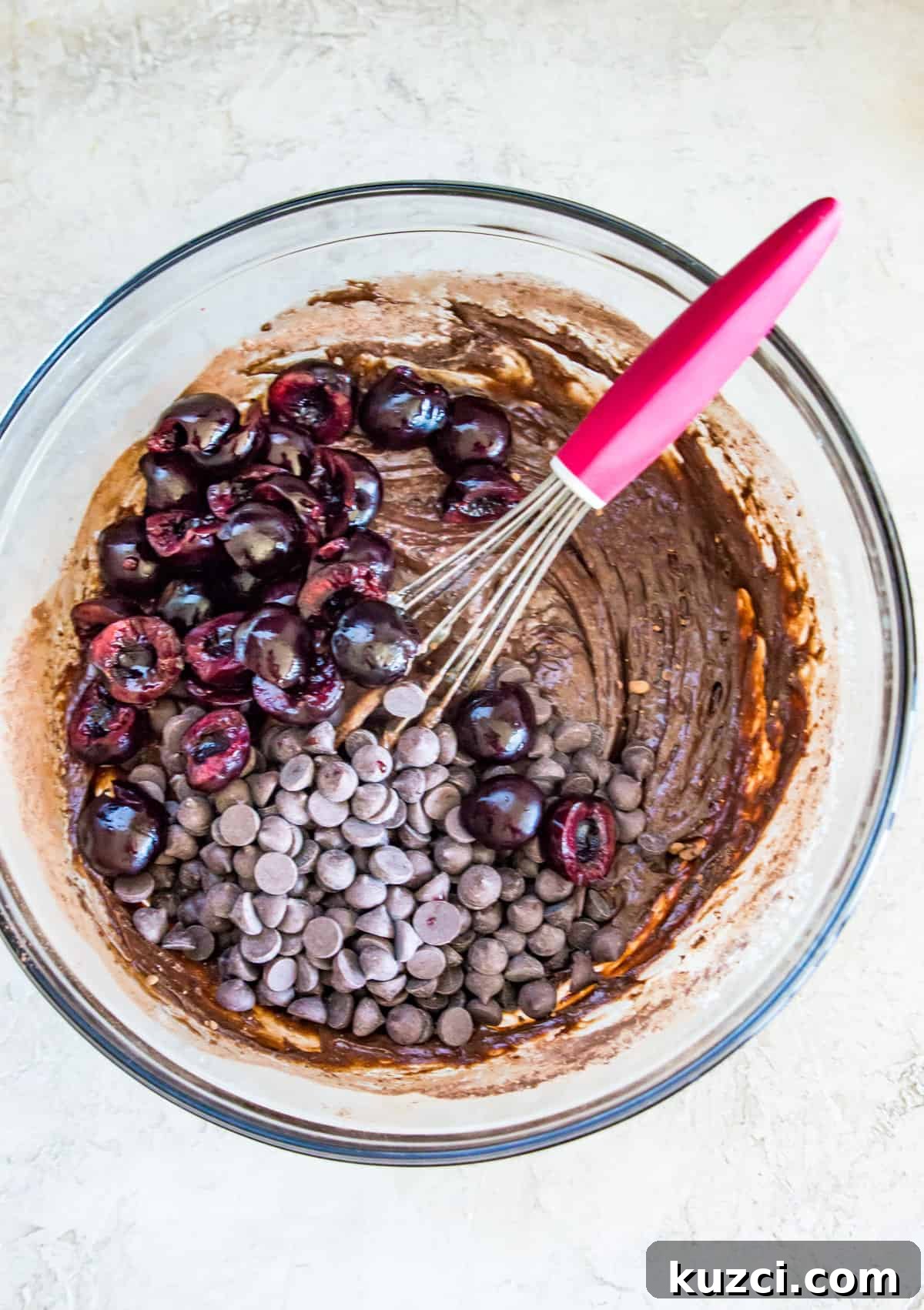 Fudgy Cherry Brownies with Dark Chocolate 7 A glass bowl with pitted cherries, chocolate chips and a chocolate batter in it.