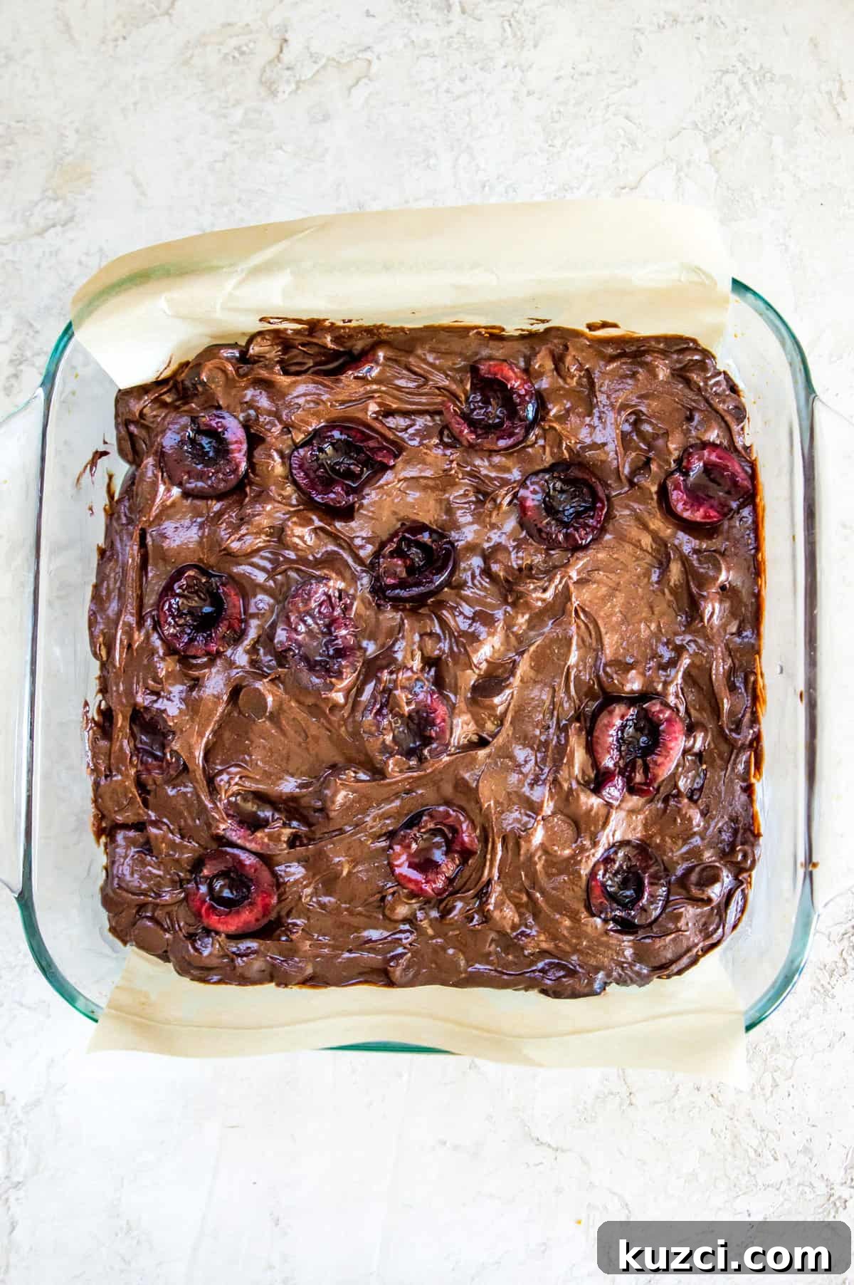 Fudgy Cherry Brownies with Dark Chocolate 8 A glass baking pan with a brownie batter topped with chopped cherries in it.