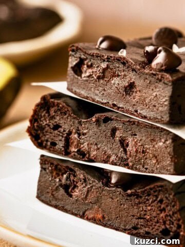A stack of three avocado brownies topped with chocolate chips on a plate.