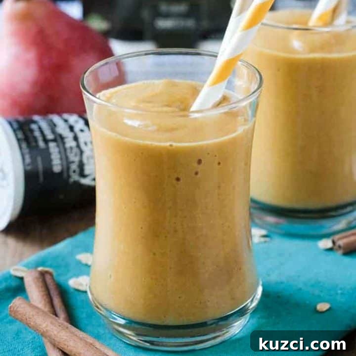 Pumpkin pear smoothie in a glass with an orange and white straw.