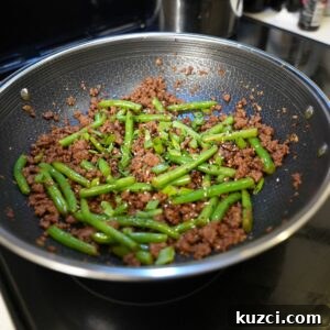 Ground Beef Stir Fry Recipe with Vegetables 8 Ground beef and green beans topped with scallions and sesame seeds in a wok.