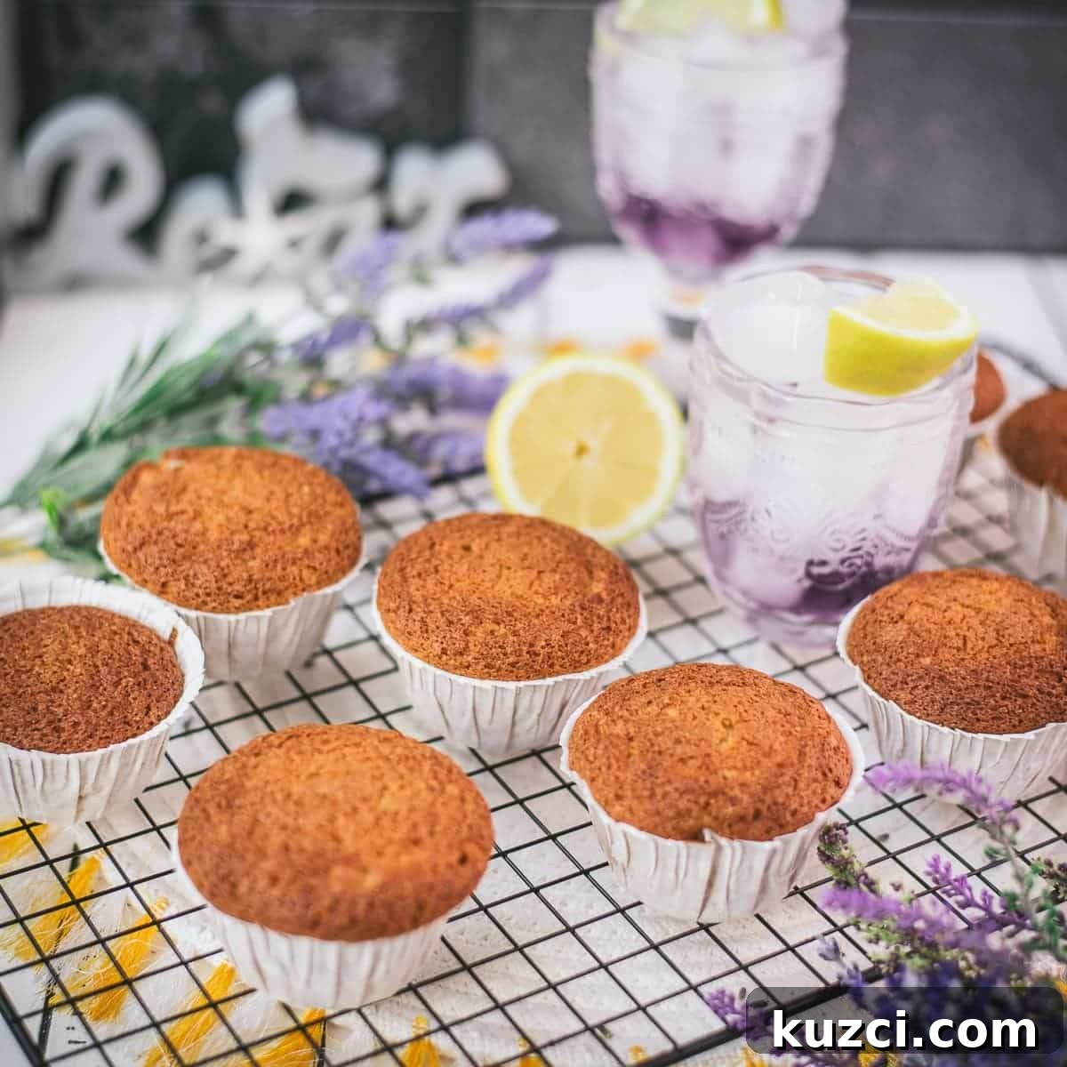 Fluffy lavender lemon muffins cooling on a rack beside a lemon.