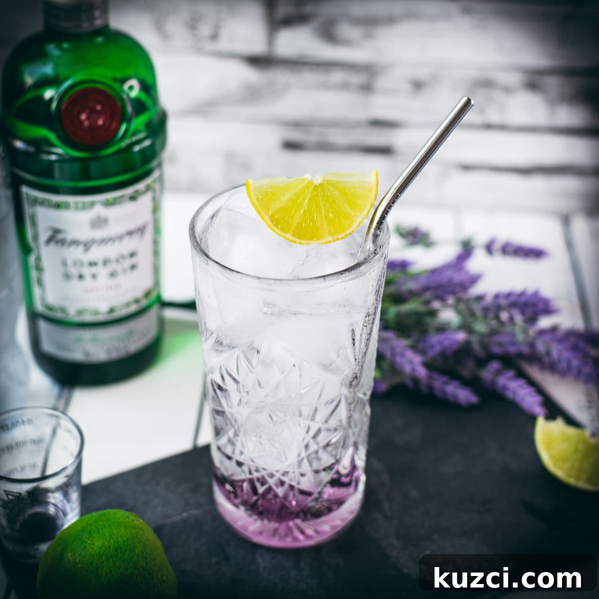 Lavender gin and tonic in a highball glass with lime garnish.