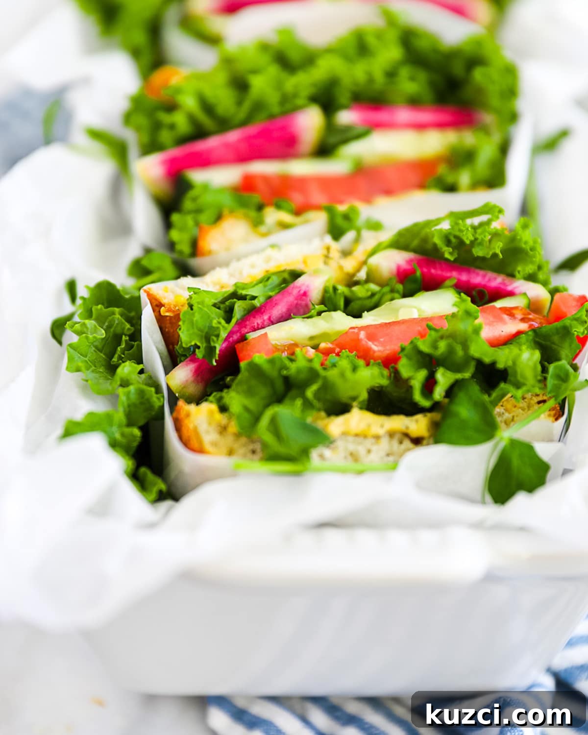 a 45 degree angle of vegetable sandwiches that are cut in half and wrapped in white paper.
